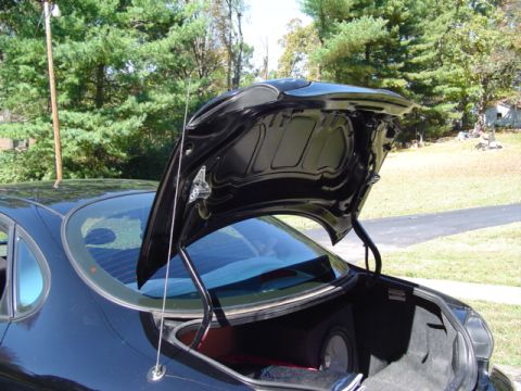 1999 Ford Taurus - Rear three-quarter view of a black sedan with the trunk lid open, exposing the painted underside of the lid with its gooseneck hinges and l…