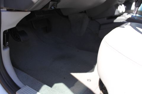 2003 Ford Crown Victoria - The interior floor of a vehicle shows pedals and a portion of a light-colored seat, with a watermark from Supermotors.net.