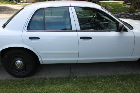 2003 Ford Crown Victoria - White 2003 Ford Crown Victoria sedan, side profile, parked on a driveway.