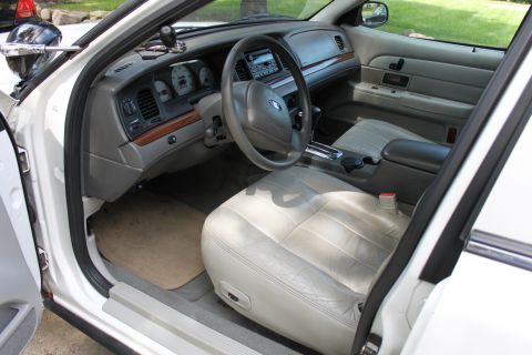 2003 Ford Crown Victoria - The interior of a white 2003 Ford Crown Victoria is shown, light-colored leather seats and wood trim accents on the dashboard.