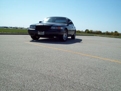 1999 Mercury Grand Marquis - Sedan parked on asphalt with a yellow line in the foreground under a clear blue sky.