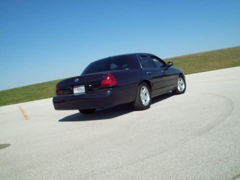 1999 Mercury Grand Marquis - Dark sedan with a distinctive taillight design and body shape, seen from the rear.