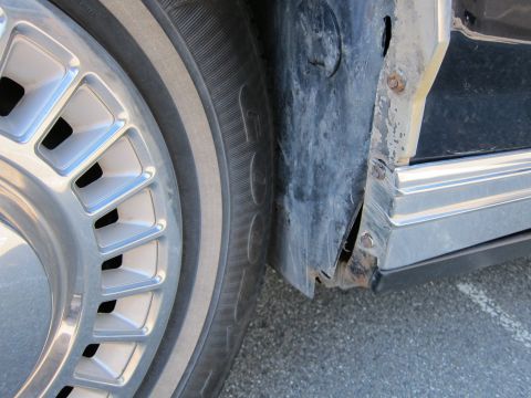 1991 Ford LTD Crown Victoria - Close-up of the wheel well and fender area on a 1991 Ford Crown Victoria LTD, revealing significant rust and damage.