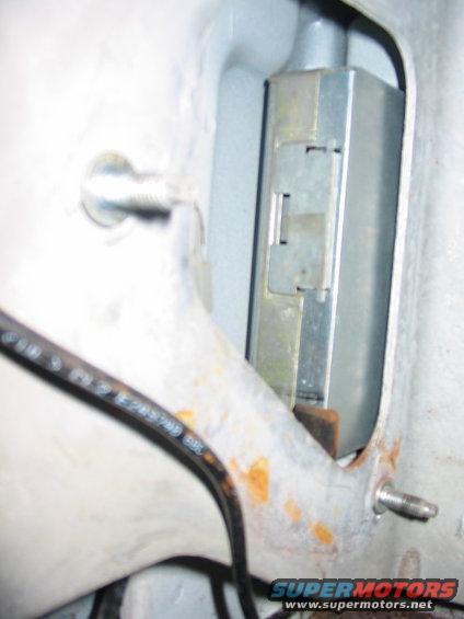 1993 Ford F-150 - A close-up view of a metal bracket and latch mechanism, with a black cable running nearby.