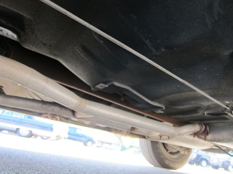 1991 Ford LTD Crown Victoria - The undercarriage of a vehicle is shown, with exhaust pipes and other mechanical components visible.