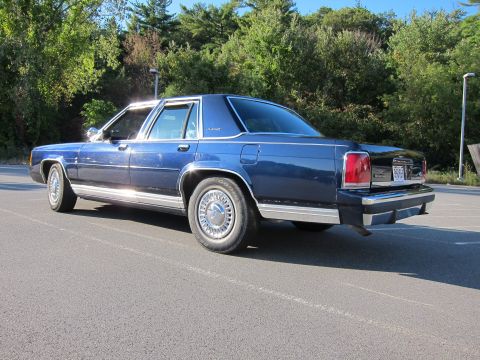 1991 Ford LTD Crown Victoria - This blue sedan is parked in an outdoor lot with trees visible behind it.