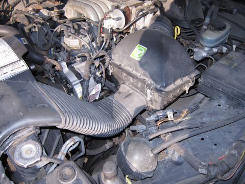 1991 Ford LTD Crown Victoria - Close-up view of a vehicle's engine bay, focusing on the air intake system and alternator.