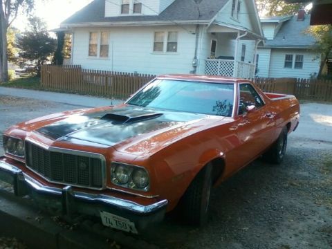 1975 Ford Ranchero - A vintage orange Ford Ranchero is parked in front of a house.