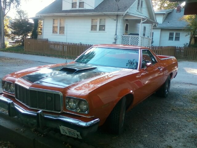 Orange 1970s Ford Ranchero with black hood stripe, front 3/4 view, parked on street