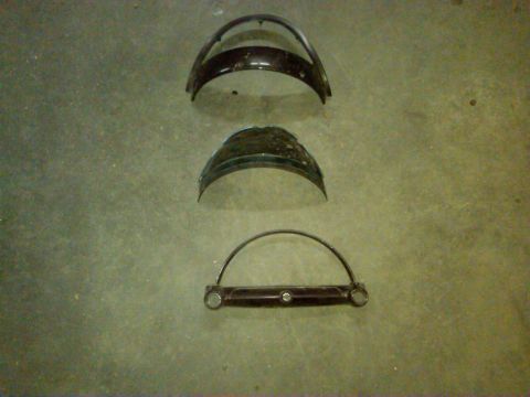 1954 Ford Customline - Several curved metal parts, likely headlight bezels, are displayed on a textured floor.
