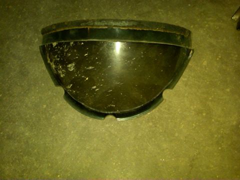 1954 Ford Customline - A dark green headlight bezel, likely for a vintage vehicle, shows signs of wear and chipped paint.