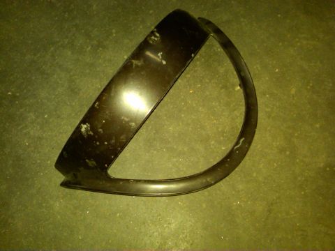 1954 Ford Customline - This is a single car part, a headlight bezel, shown on a floor.