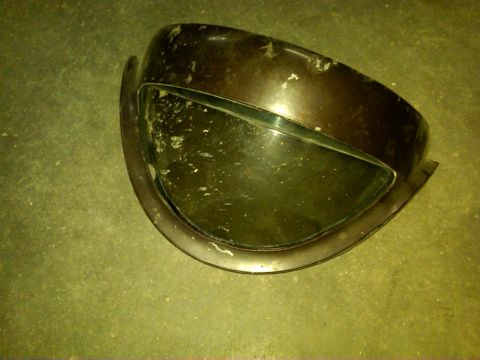 1954 Ford Customline - A detached car headlight assembly sits on a textured green floor, showing signs of wear.