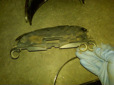 1954 Ford Customline - A gloved hand holds a black plastic car part with two circular openings.