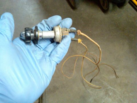 1954 Ford Customline - A gloved hand holds a headlight bulb socket with exposed and frayed wires, suggesting a part removed from a vehicle.
