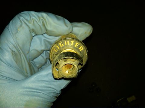 1954 Ford Customline - A gloved hand holds a vintage cigarette lighter part, showing the word "LIGHTER" in yellow lettering.