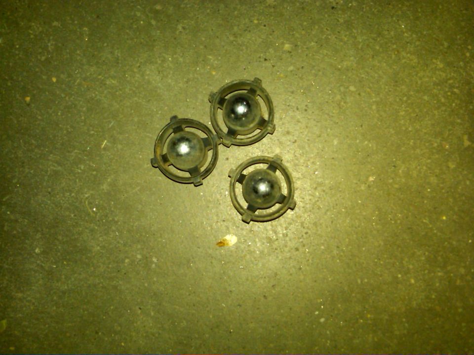 Three round metal fasteners with glass spheres on a textured surface
