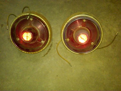1954 Ford Customline - Two round red taillights with chrome bezels and attached wiring are shown, likely for a vintage vehicle.