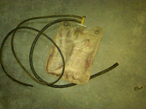 1954 Ford Customline - A dirty, beige windshield washer fluid bag with two black hoses lies on a concrete surface.