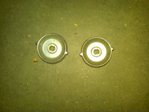 1954 Ford Customline - Two metal caps with central holes are shown on a textured surface.