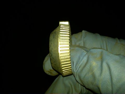 1954 Ford Customline - A gloved hand holds a ribbed, brass-colored gas cap against a dark background.