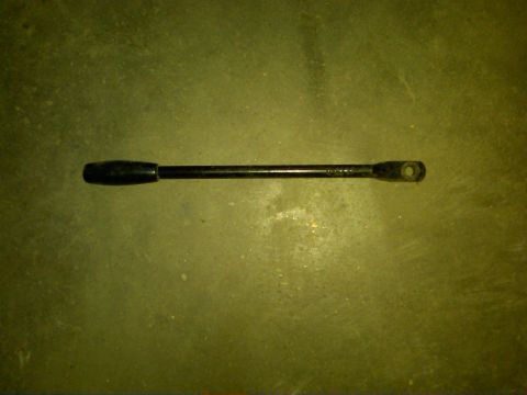 1954 Ford Customline - A black automotive part with a knob and a hole is shown against a textured background.