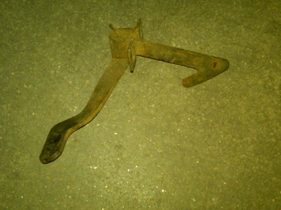 Rusted metal lever mechanism on a speckled green surface