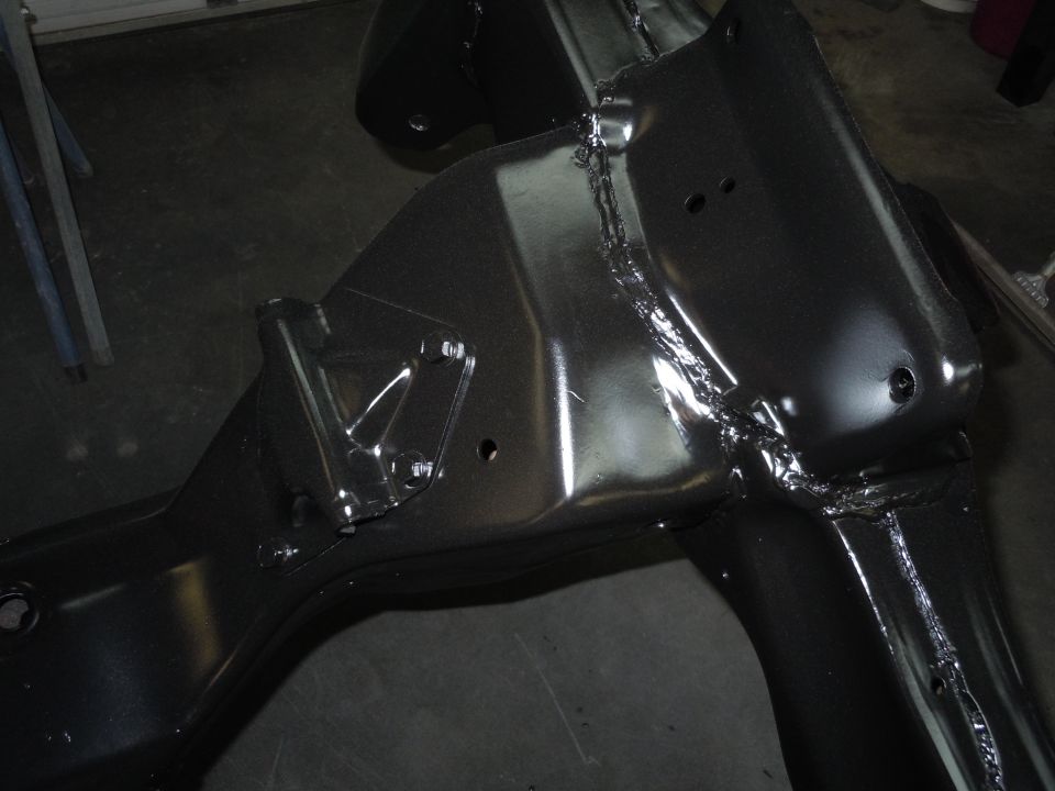 Close-up of a black painted car frame section with visible welds