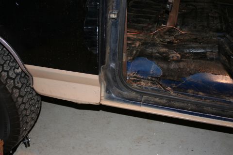 1989 Ford Bronco - Interior view of a vehicle, focusing on the door jamb and floor. A tire is visible on the left side.