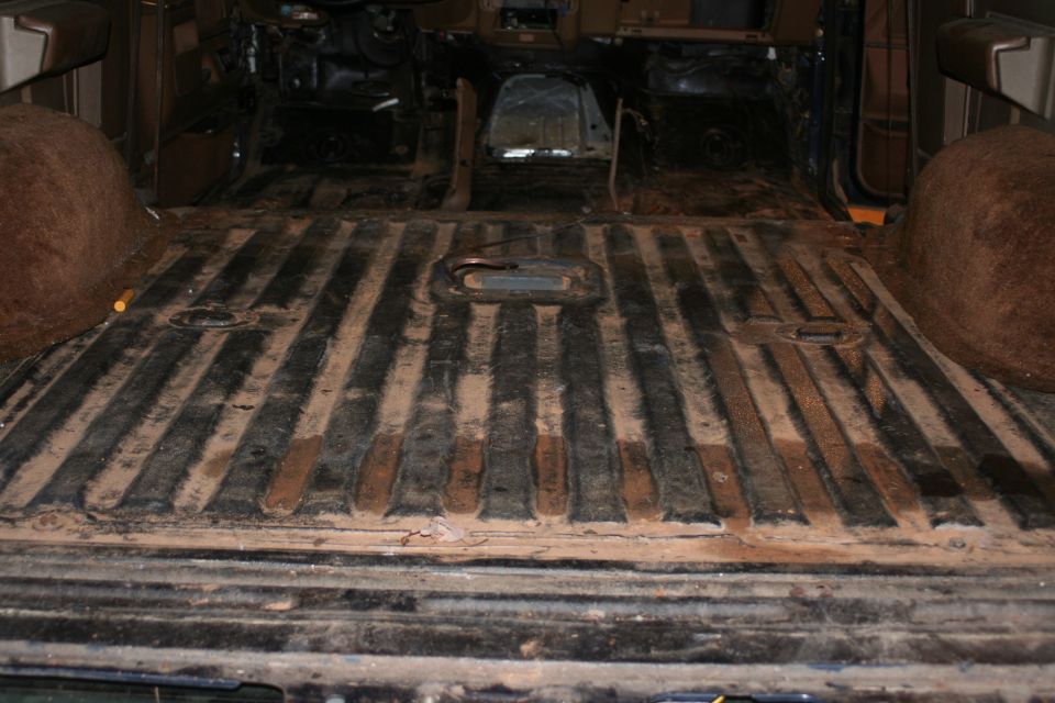 Vehicle interior with ribbed floor, brown wheel wells, and exposed metal