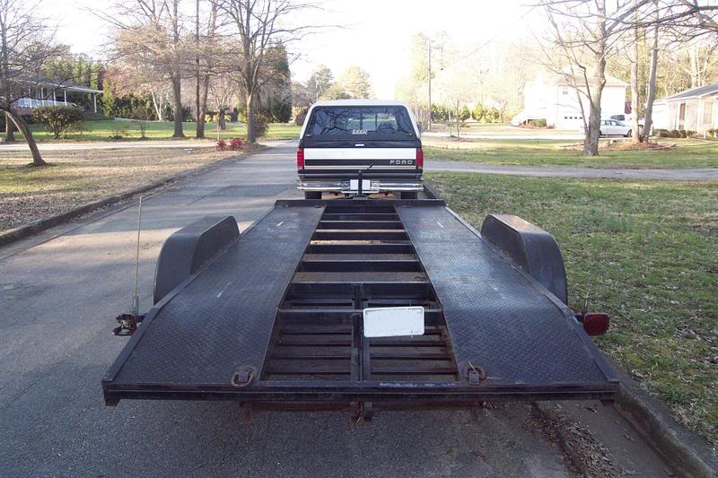 Rear view of a 1992 Ford F-150 pickup truck on a car hauler trailer, parked on a residential street