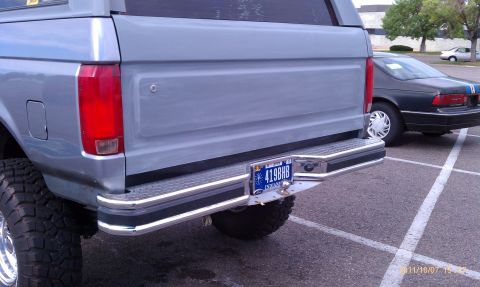 1994 Ford Bronco - The rear of a light blue Ford Bronco is shown, with a chrome bumper and a trailer hitch visible.