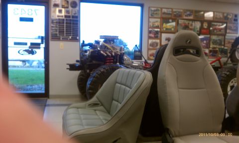 1994 Ford Bronco - An off-road vehicle chassis is displayed indoors with racing seats in the foreground.
