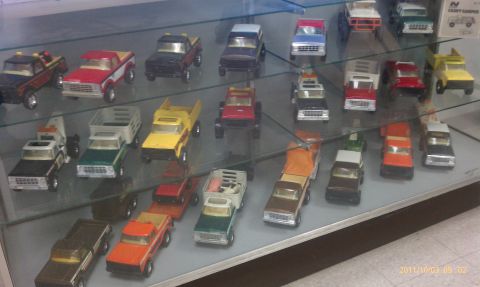 1994 Ford Bronco - Various toy trucks and SUVs are displayed on glass shelves in a collection.
