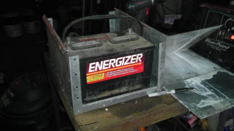 1989 Ford Bronco - A car battery is held in a metal enclosure, possibly for a custom installation or project.