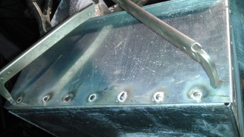 1989 Ford Bronco - A close-up view of a metal panel undergoing welding, secured by clamps.