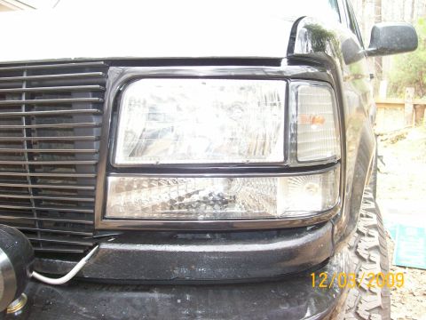 1996 Ford Bronco - The front grille and headlight assembly of a black Ford truck is shown in this close-up view.