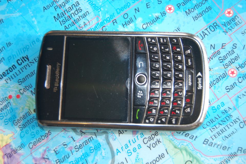 BlackBerry phone with a QWERTY keyboard lying on a world map