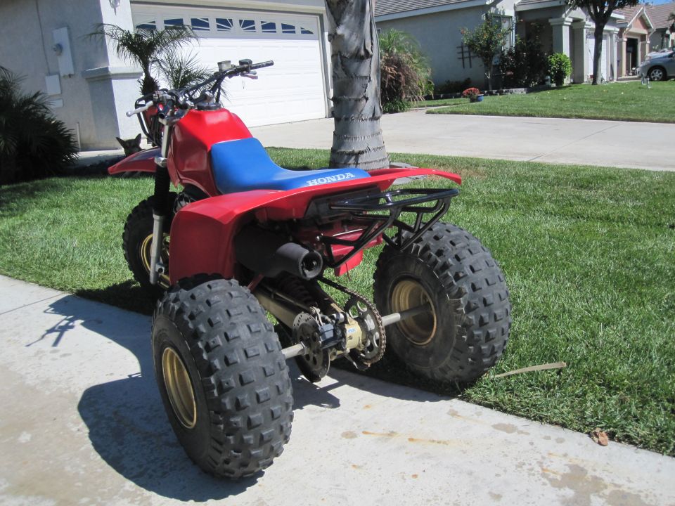 1983 Honda 250 R ATV, red body with blue seat, parked on a driveway