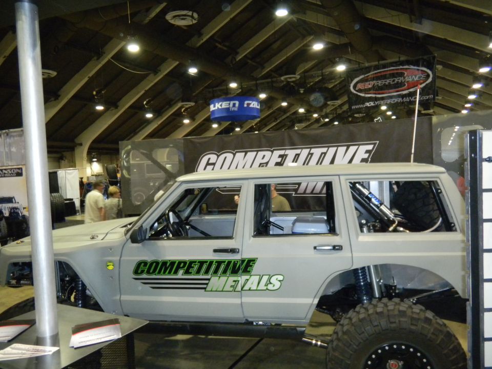 custom SUV with 'COMPETITIVE METALS' on the side, large tires, and exposed suspension