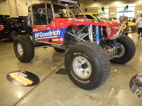 1997 Ford Ranger - This heavily modified off-road buggy features BFGoodrich tires and a prominent roll cage, seen at an indoor event.