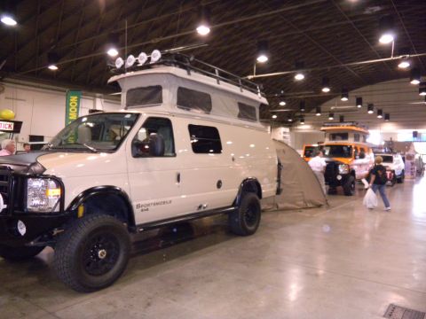 1997 Ford Ranger - A Ford E-Series van converted into a camper with a pop-top roof is displayed at an indoor event.