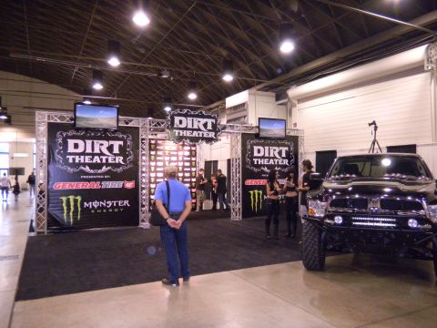 1997 Ford Ranger - A modified black truck is displayed at an indoor event with a 'Dirt Theater' sponsorship booth.