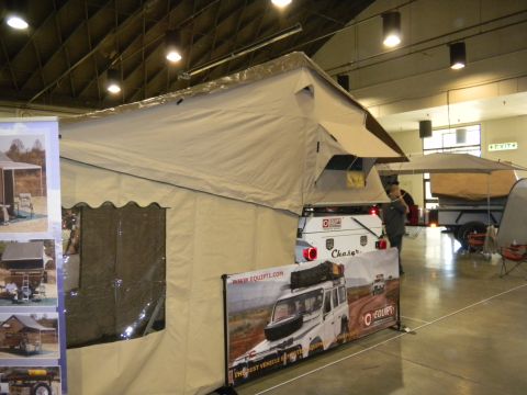 1997 Ford Ranger - A pop-up camper trailer with an attached tent is displayed indoors, a white trailer with visible branding.