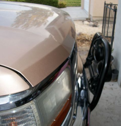 1996 Ford Bronco - Close-up of a tan SUV's front corner, a bull bar and chrome accents. The body style suggests a 1996 Ford Bronco.