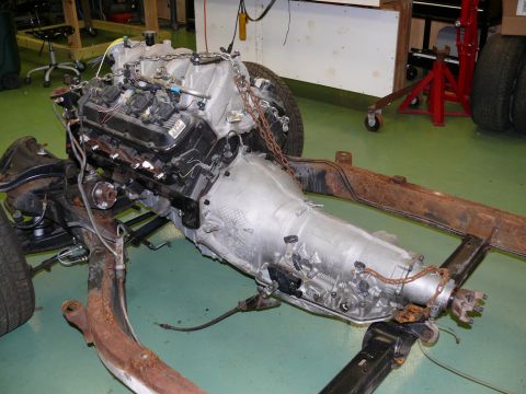 1976 Chevrolet Corvette - Engine and transmission assembly is suspended by chains and resting on a frame in a workshop.