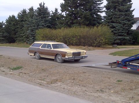 1978 Mercury Colony Park - A station wagon with wood paneling is being loaded onto a trailer on a suburban street.