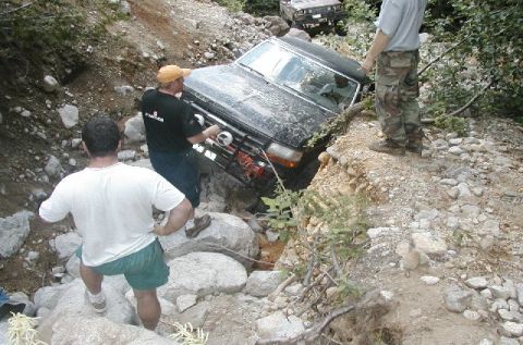1993 Ford Bronco - A 1993 Ford Bronco is stuck in a rocky ditch while people attempt to help it.