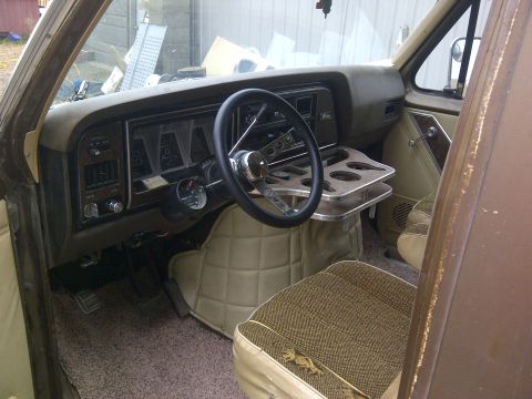 1979 Ford E250 - The interior of a 1979 Ford E250 van features a brown dashboard, a custom steering wheel, and quilted seating.