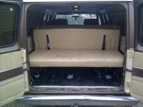 1979 Ford E250 - The rear interior of a van is visible, a bench seat and the open rear doors.